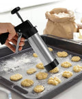 Cookie press being used to shape dough onto a baking tray