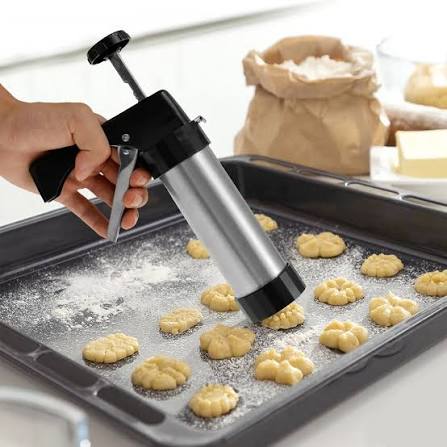 Cookie press being used to shape dough onto a baking tray